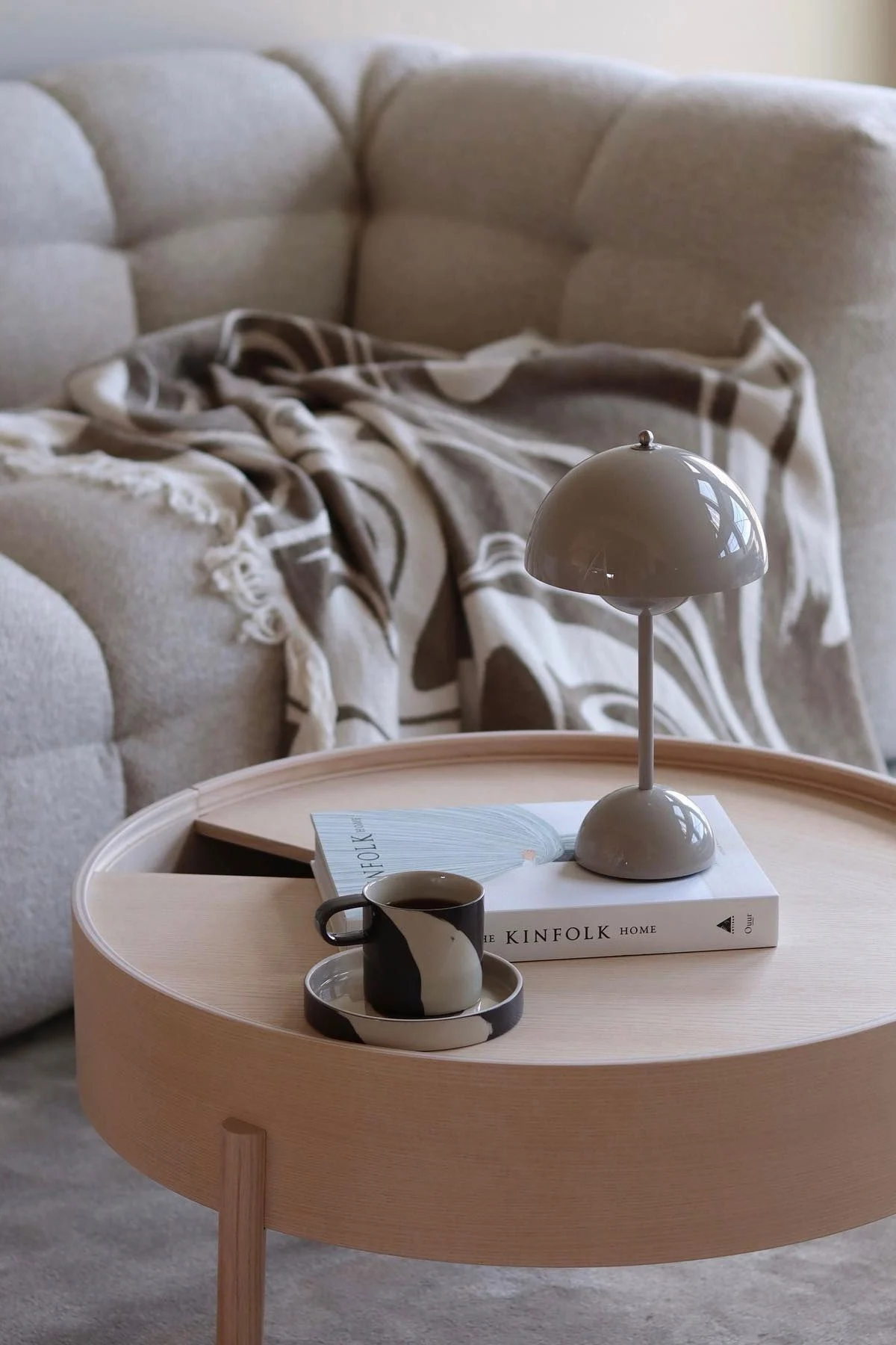 Ein Couchtisch aus Holz ist dekoriert mit einem Buch, einer Flowerpot Tischlampe von &Tradition und der Inlay Tasse von Ferm Living.