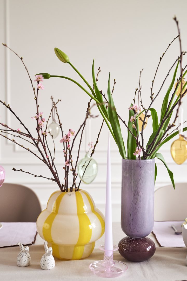 Kreieren Sie einen festlichen Ostertisch in Pastellfarben mit zarten Glaseiern von Iittala, die an Zweigen hängen, welche in der Curlie-Vase von By On neben der Dorit-Vase von Broste Copenhagen stehen.