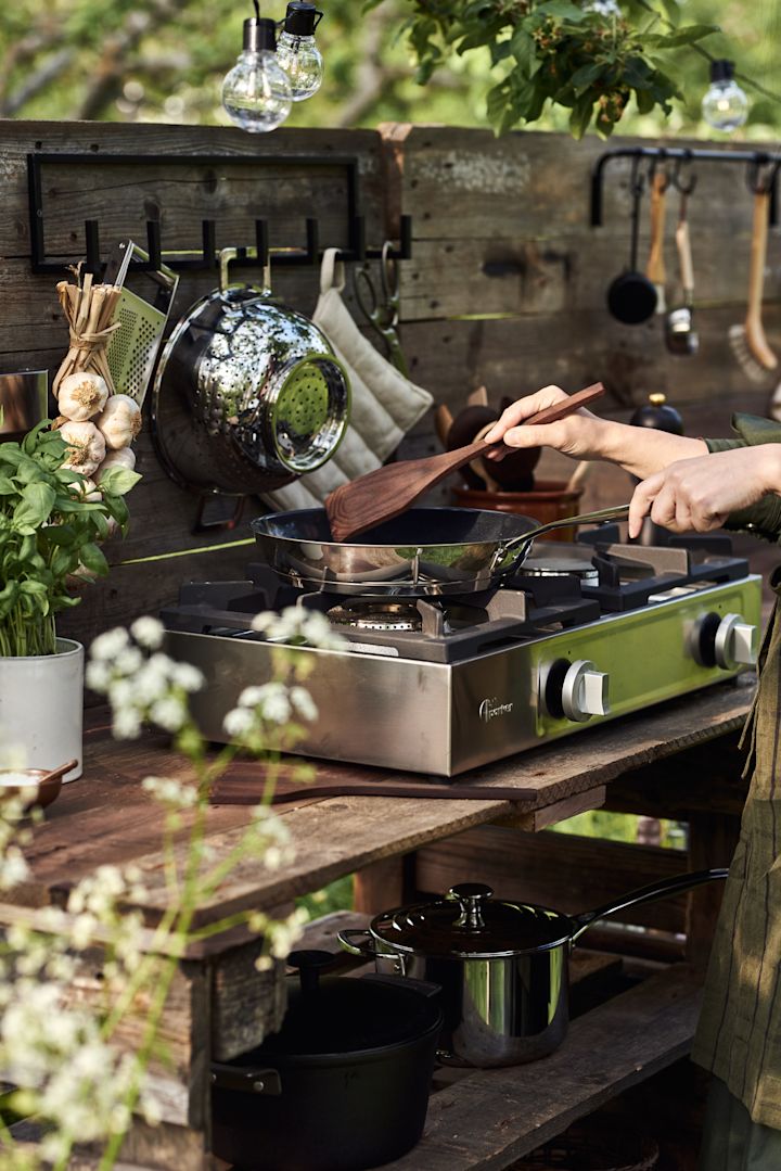 Kochen im Freien sollte auf jeder Summer Bucket List stehen. Hier sehen Sie jemanden, der in einer selbstgebauten Outdoor-Küche kocht.