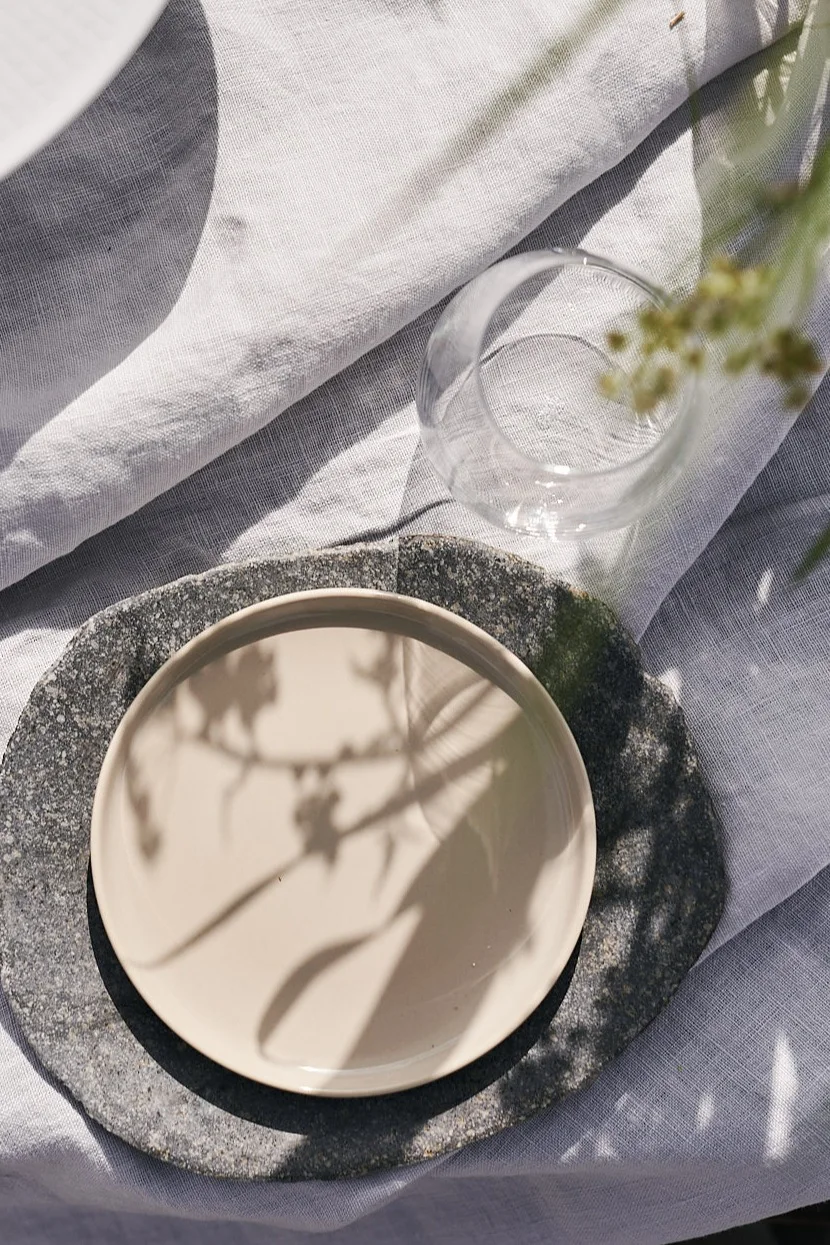 Strapazierfähige Teller von Muubs & Marimekko auf einer weißen Leinentischdecke eignen sich hervorragend, um den Tisch für ein luxuriöses Picknick am Strand zu decken.