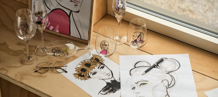 Die All about you-Kollektion, von Sara Woodrow für Kosta Boda entworfen: Hier sehen Sie einige ihrer Entwürfe und eine Sammlung von Gläsern aus der Kollektion auf einem Holztisch.