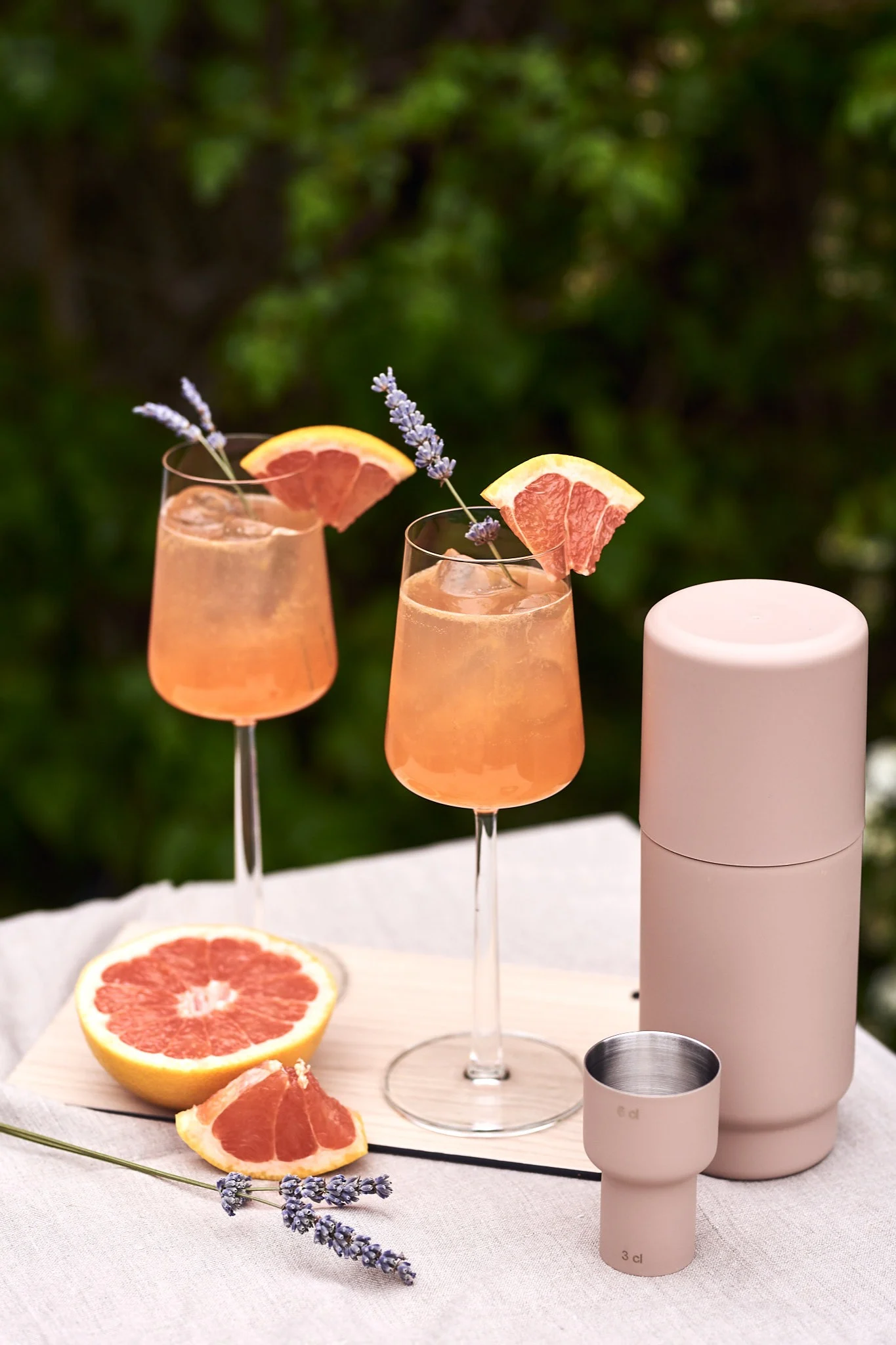 Erfrischende Sommergetränke mit Grapefruit in Essence-Gläsern von Ittala auf einem Tisch im Freien.