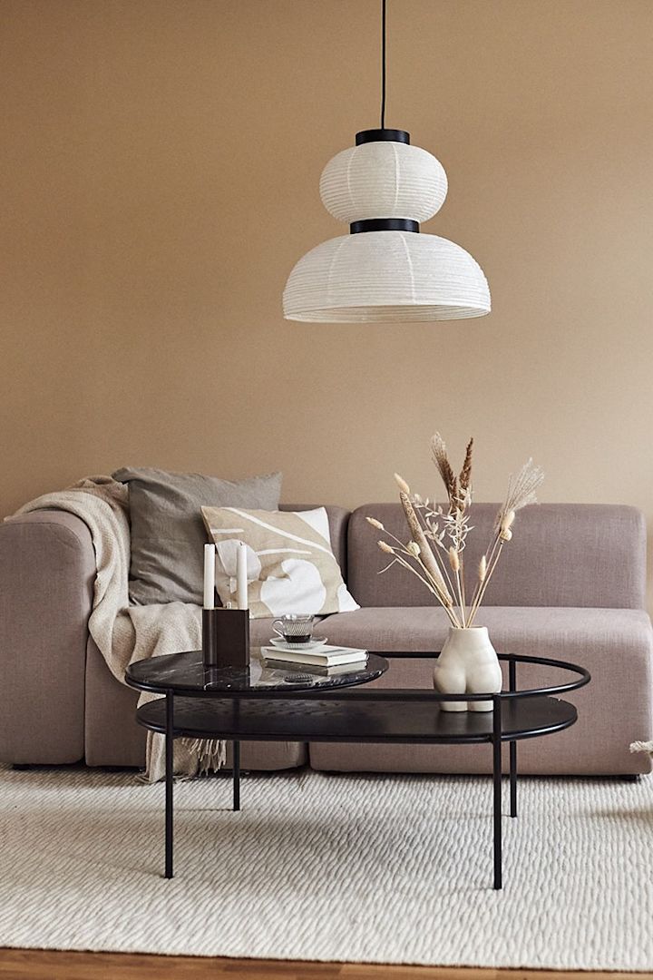 Wohnzimmer im japanischen Stil mit Reislampe, schwarzem Couchtisch und Sofa in klaren Linien.