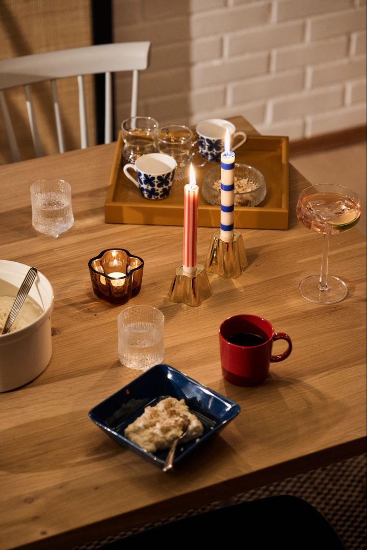 Schwedisches Weihnachtsessen: Ein festlicher, schwedischer rot-blau gedeckter Weihnachtstisch mit einer blauen Schale mit Ris a la Malta, einer passenden roten Tasse und blauen und roten Kerzen. 