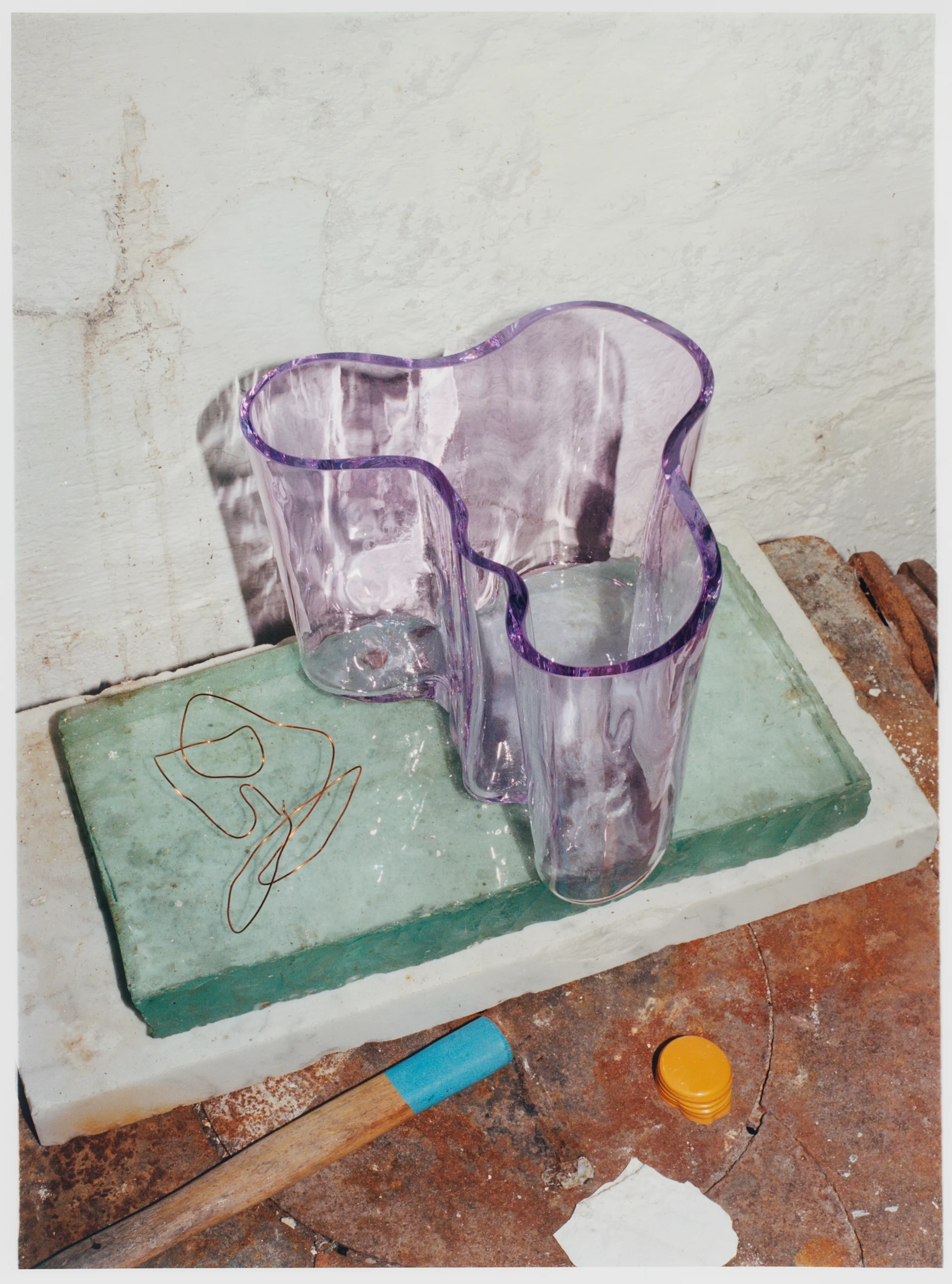 Alvar Aalto Vase von Iittala in einem hellen lila Farbton auf Felsen stehend.