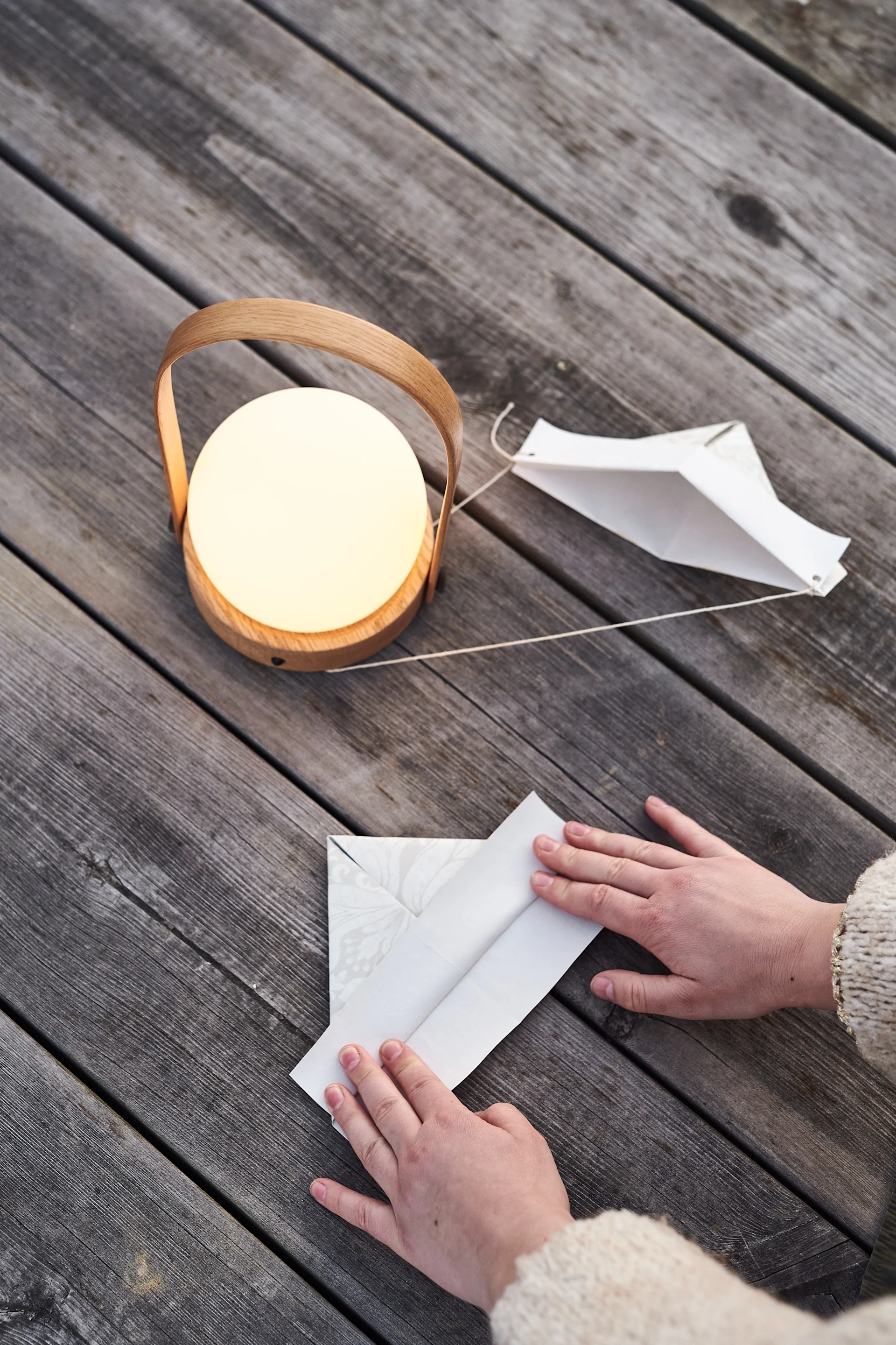 Basteln Sie mit Ihren Gästen Papierhüte zum Krebsfest, hier sehen Sie ein paar Hände, die gerade einen Hut falten.