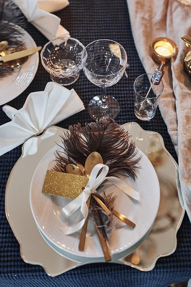 Ideen für Ihre Silvesterparty: Decken Sie den Tisch glamourös, zum Beispiel im Stil von Gatsby in Goldtönen und einer Feder.