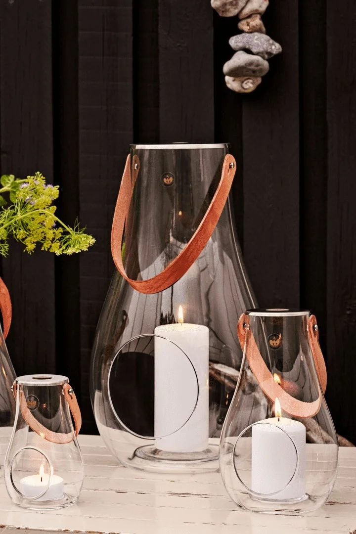 Platzieren Sie die Laternen und Windlichter für draußen am besten in Gruppen. Hier sehen Sie die Design with Lights-Laterne von Holmegaard in verschiedenen Größen.