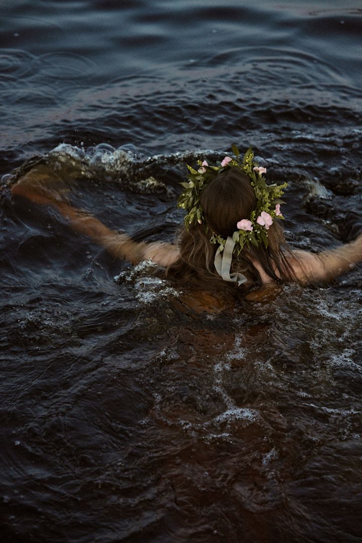 Ein Bad im nächstgelegenen See ist ein Muss während des Mittsommerfestes 2025, hier sehen Sie eine Frau mit Mittsommerkranz schwimmen.