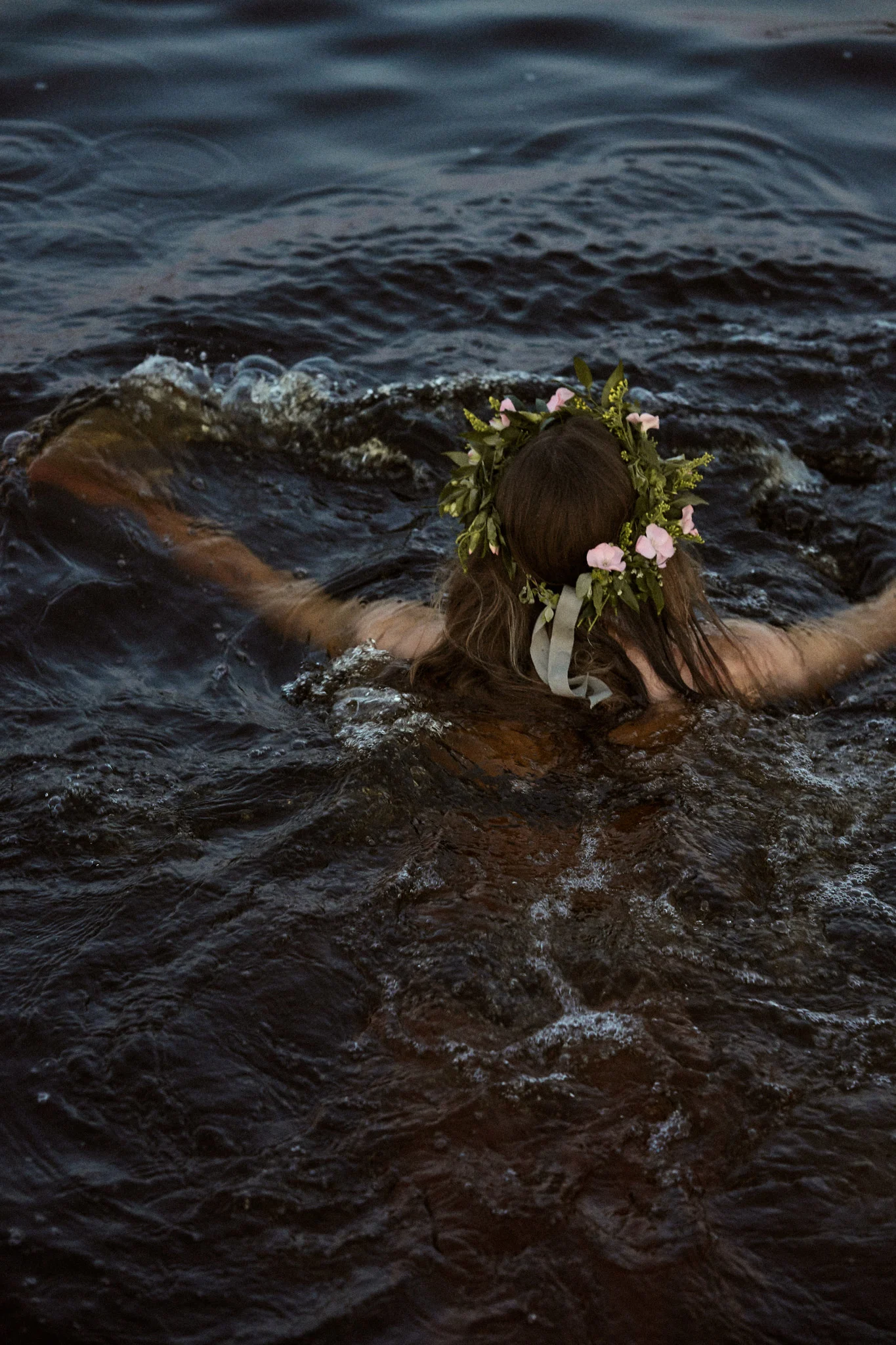 Ein Bad im nächstgelegenen See ist ein Muss während des Mittsommerfestes 2025, hier sehen Sie eine Frau mit Mittsommerkranz schwimmen.
