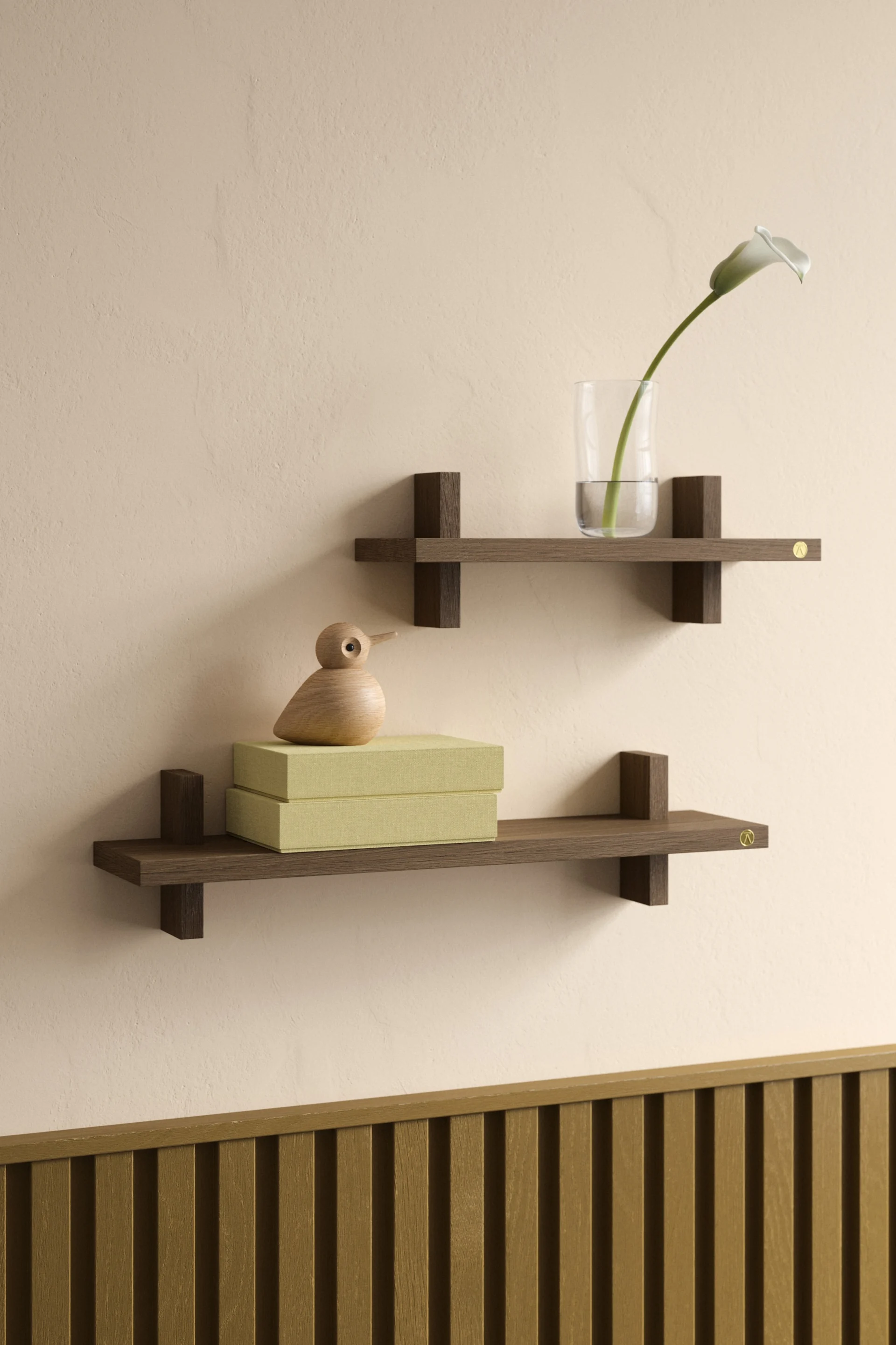 Zwei schwebende Regale aus dunklem Holz an einer beigefarbenen Wand, eines mit Vase und Lilie, das andere mit grünen Boxen und einem Holzvogel.
