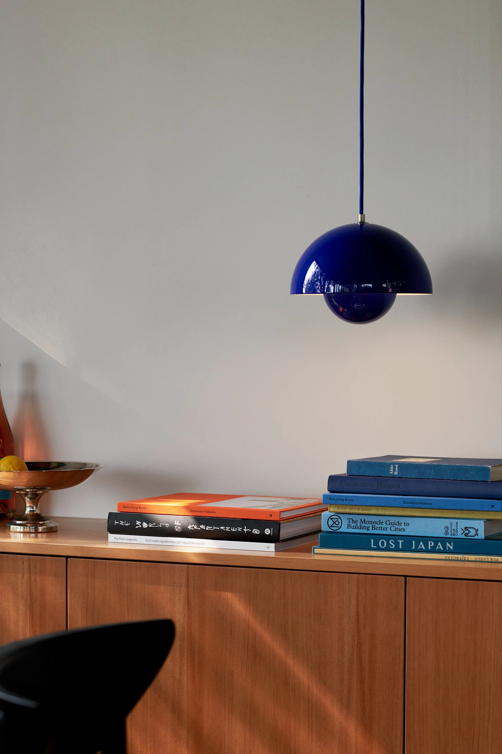 Die richtige Deckenleuchte fürs Wohnzimmer finden: Hier sehen Sie die kobaltblaue Flowerpot-VP1-Pendelleuchte von &Tradition über einem Sideboard hängen.