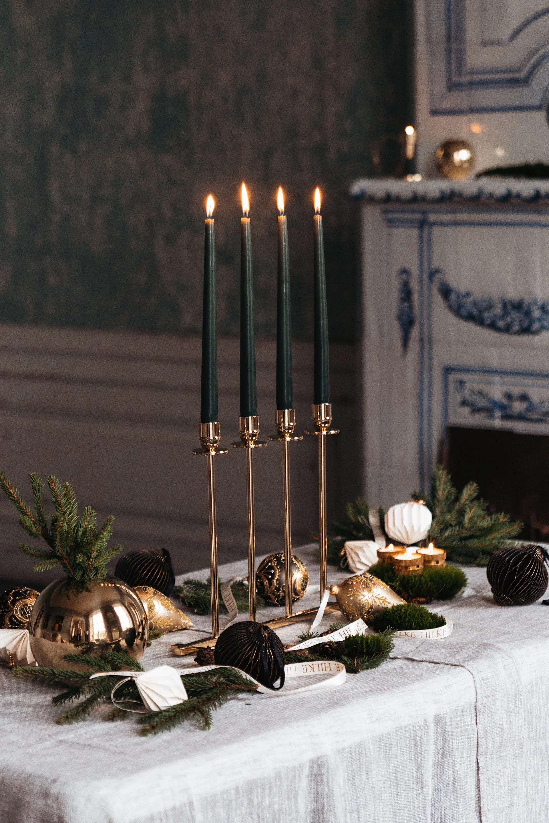 Auf einem weihnachtlich gedeckten Tisch steht der Alto Kerzenhalter von Hilke mit grünen Kerzen darin.