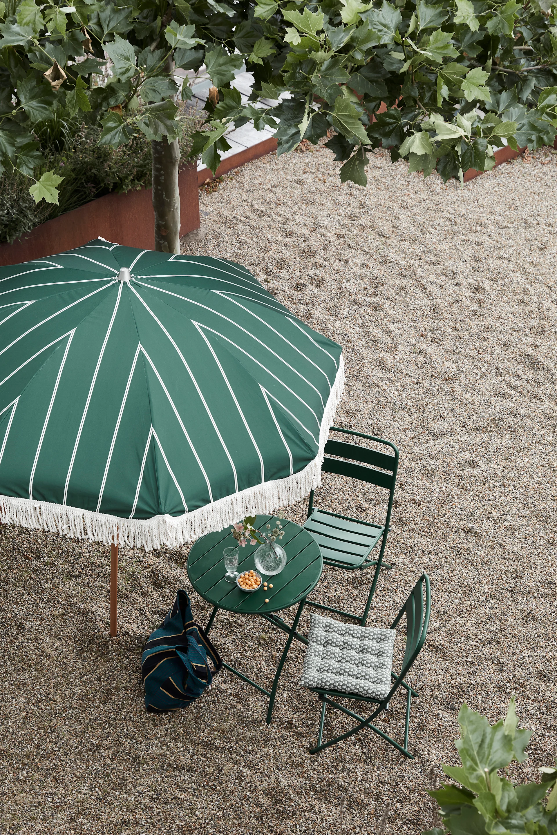 Balkon Ideen: Denken Sie unbedingt auch an den Schutz vor der Sonne in Form eines Sonnenschirms! Hier sehen Sie den Block-Sonnenschirm in Grün mit Fransenrand von House Doctor – ein kleinerer Sonnenschirm, der für einen Balkon oder eine kleine Terrasse geeignet ist.