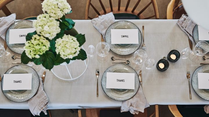 Der Tisch ist mit Nordic Sand-Tellern von Broste Copenhagen und Silberbesteck von Gense gedeckt - ein eleganter Tisch für das Sommerfest in Weiß.