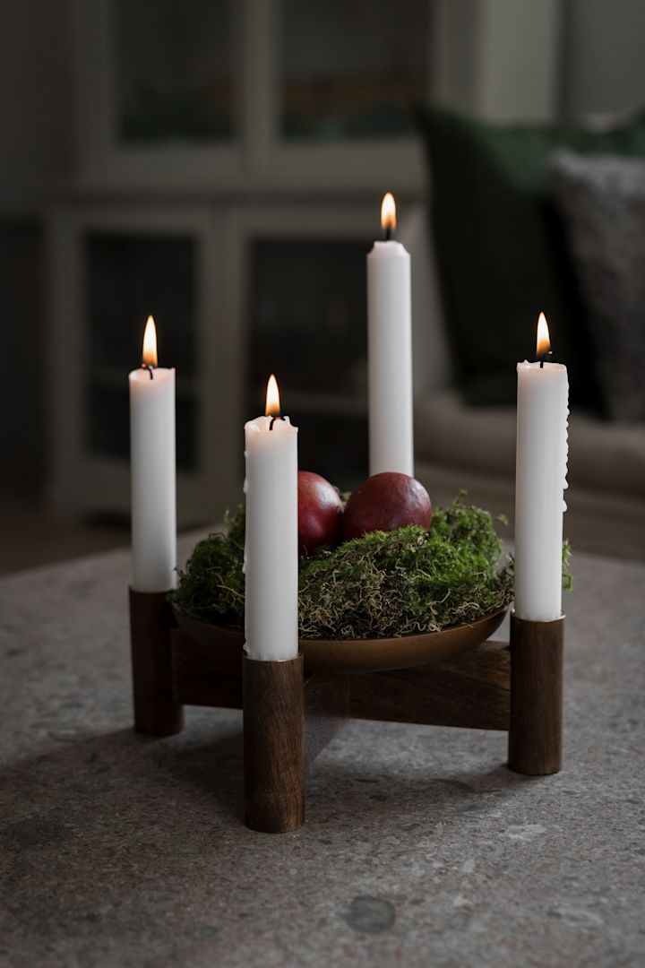 Skandinavische Adventskerzenhalter gehören zum Weihnachtsfest. Hier steht der weihnachtlich dekorierte Ernst Adventsleuchter auf einem Tisch.