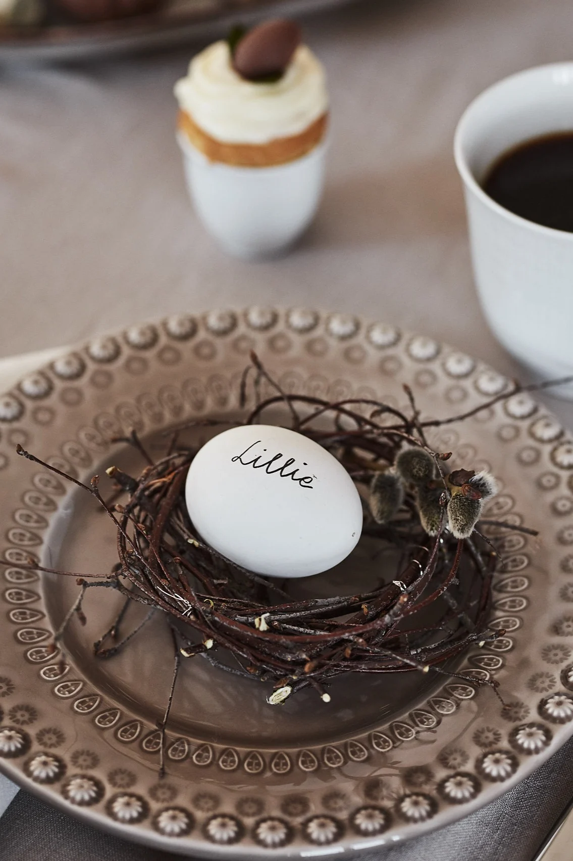 Basteln Sie zu Ostern aus Birkenzweigen ein kleines Vogelnest, legen Sie es auf einen Teller und platzieren Sie ein mit Namen beschriftetes Ei darin.