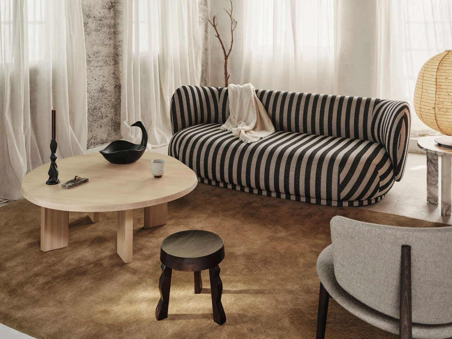 Gemütliches Wohnzimmer mit schwarz-weiß gestreiftem Sofa, hellem Holztisch und rustikaler Holzbalkendecke.