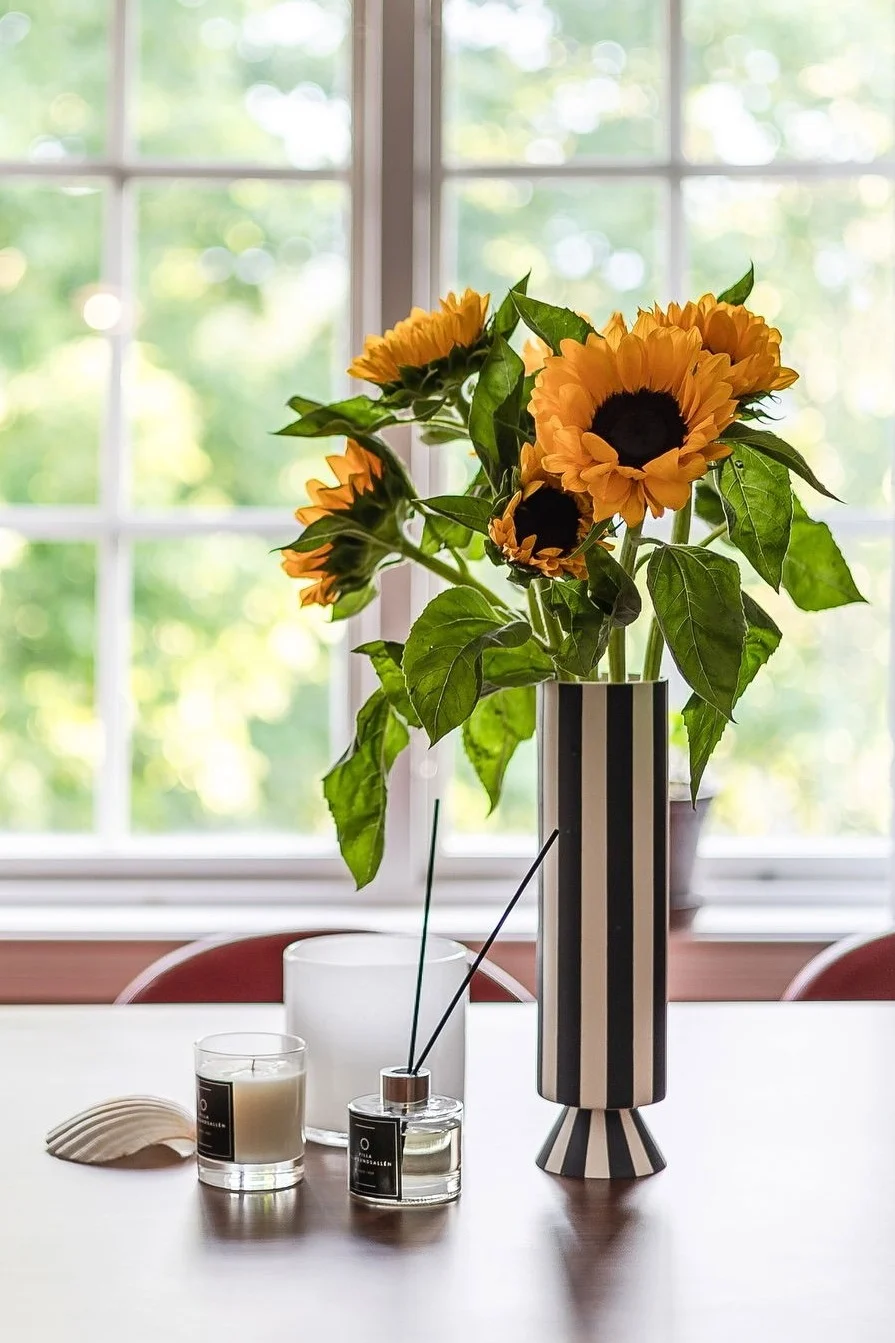 Die beste Vase für langstielige Blumen. Hier sehen Sie eine hohe Vase mit schwarzen und weißen Streifen, gefüllt mit Sonnenblumen. 