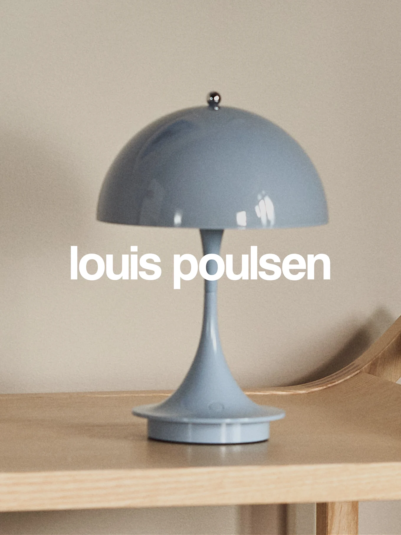 Hellblaue pilzförmige Tischlampe auf einer Holzoberfläche mit dem Text 'louis poulsen'.