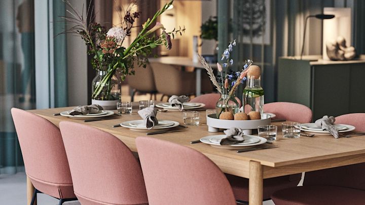 Ein festlich gedeckter Tisch mit weißem Porzellan, einer Vase und rosa Stühlen von Muuto heißt die Gäste im Büro willkommen.