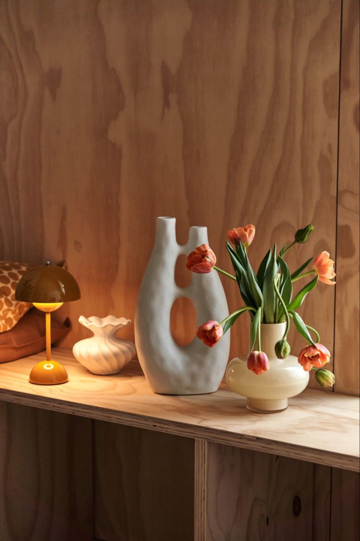 Frühlingserwachen: Hier sehen Sie eine Kommode mit einer tragbaren Leuchte, einer Skulptur und einer Vase mit frischen Blumen, um einen Raum optisch interessant zu gestalten.