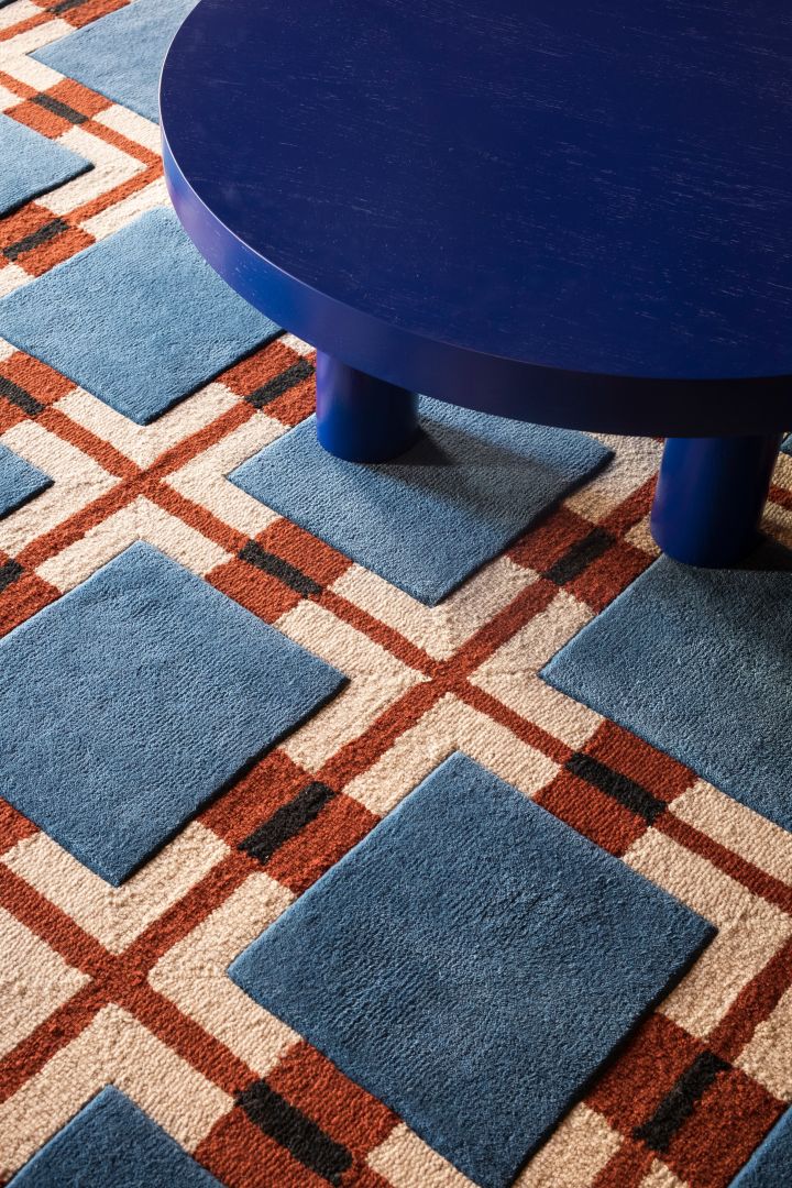 Die Kombination von Farben und Mustern auf Textilien und Teppichen ist ein großer Teil der skandinavischen Wohntrends 2024, hier in einem rot-blauen Wollteppich mit geometrischem Muster von Layered.