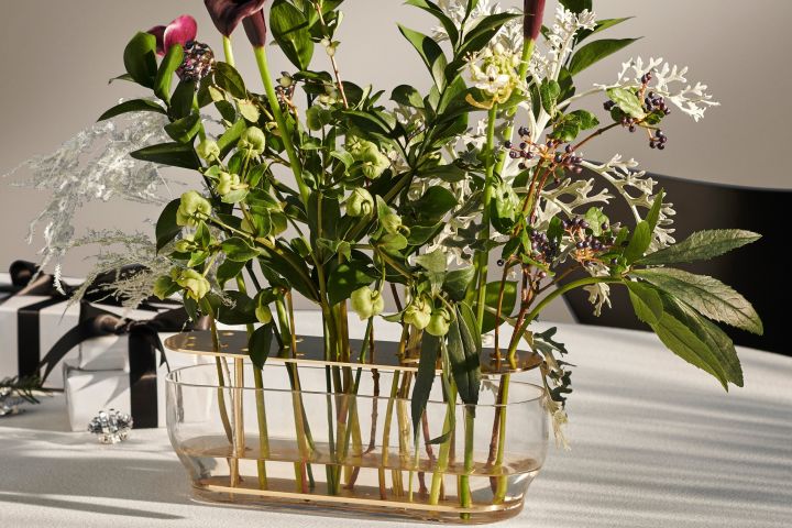 Eine Nahaufnahme der länglichen Ikebana Vase von Fritz Hansen mit zahlreichen Blumen darin.