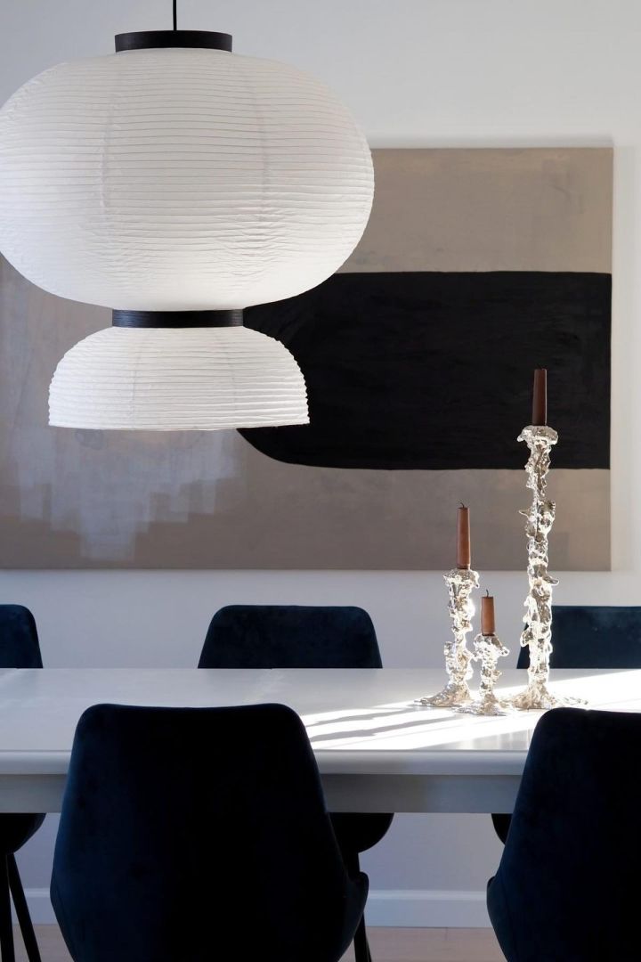 11 stylische Pendelleuchten für Ihr Wohlfühlzuhause - hier sehen Sie die Formakami-Pendelleuchte von &Tradition über einem schwarz-weißen Esstisch hängen. 