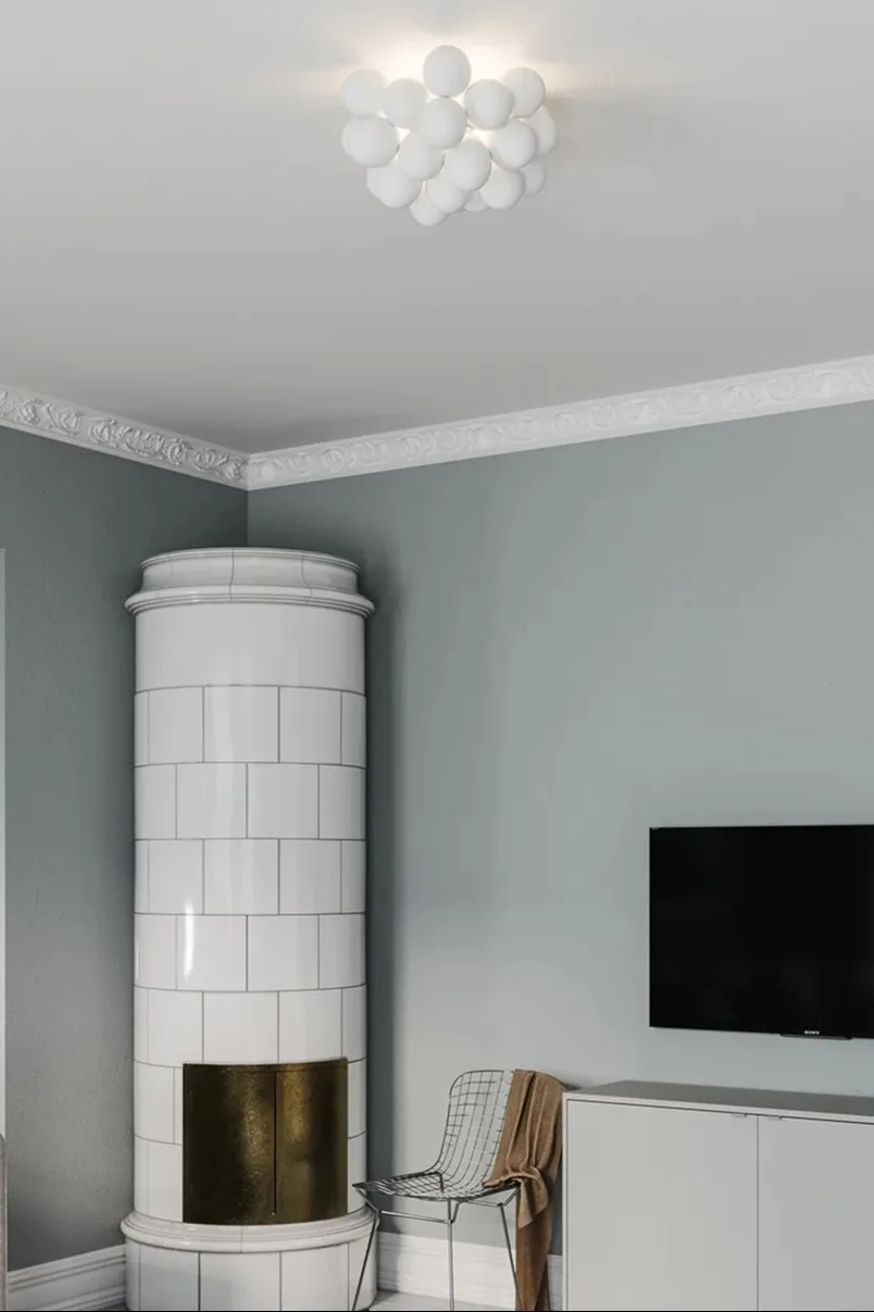 Die richtige Deckenleuchte fürs Wohnzimmer finden: Hier sehen Sie die weiße Gross Deckenleuchte von By Rydéns in einem Wohnzimmer mit einem Kachelofen.