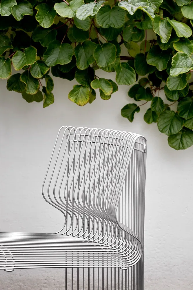 Eingerahmt von rankenden Pflanzen steht ein Teil des Panonova Modulsofas im Freien.