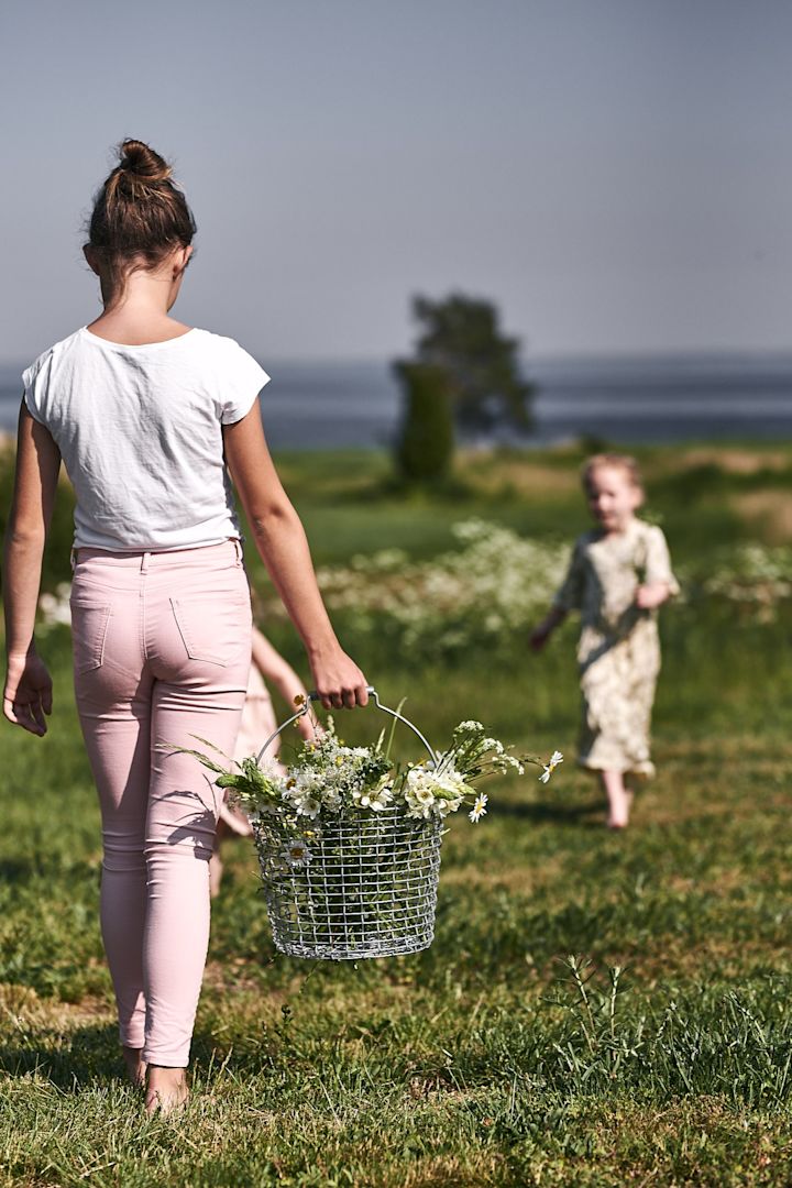 Kinder pflücken Wildblumen auf der Wiese, um für das Gartenfest Blumenarrangements zu gestalten. 