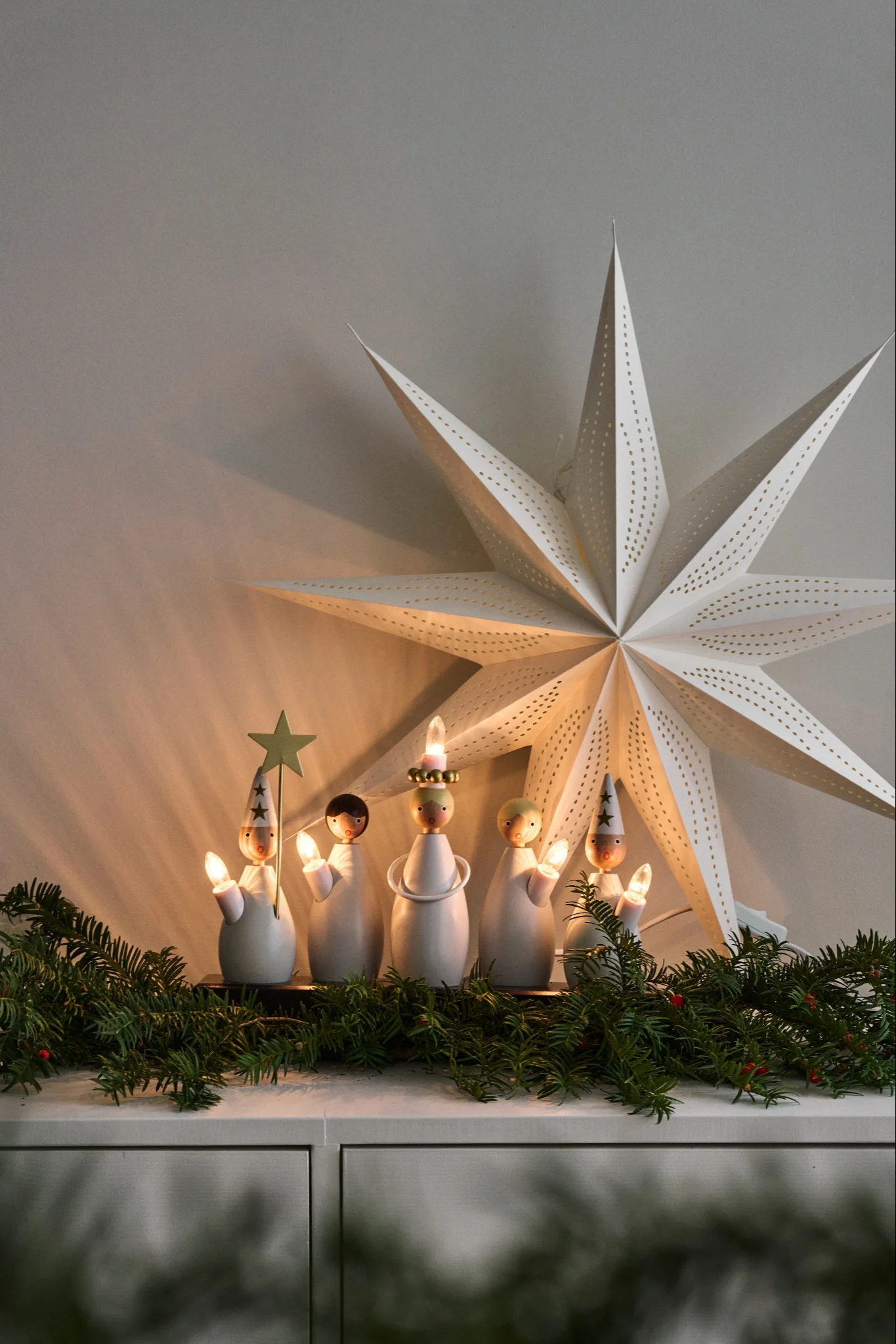 Der Lucia-Kerzenhalter von Star Trading steht auf einer mit Tannengrün dekorierten Kommode.