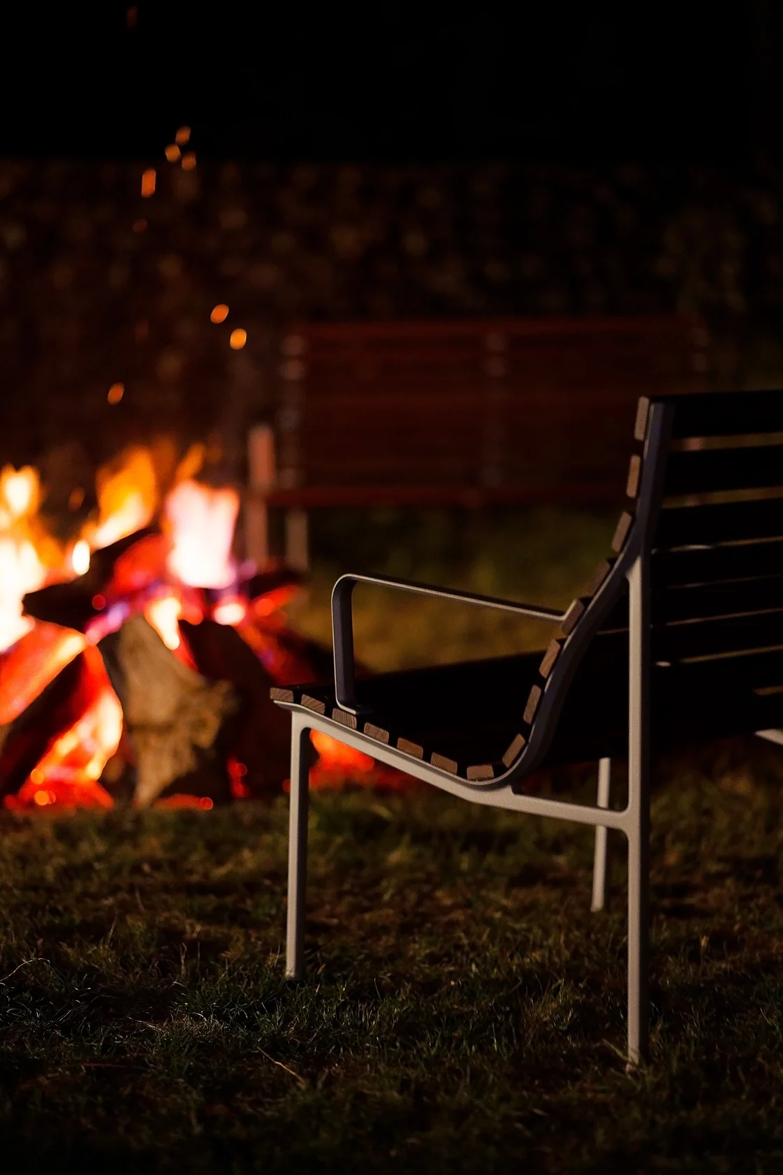 Ein gemütliches Lagerfeuer zu machen sollte auf Ihrer Herbst To-do-Liste ganz weit oben stehen. Hier auf dem Bild steht der Traverse Lounge-Armlehnenstuhl von HAY vor einem Lagerfeuer.