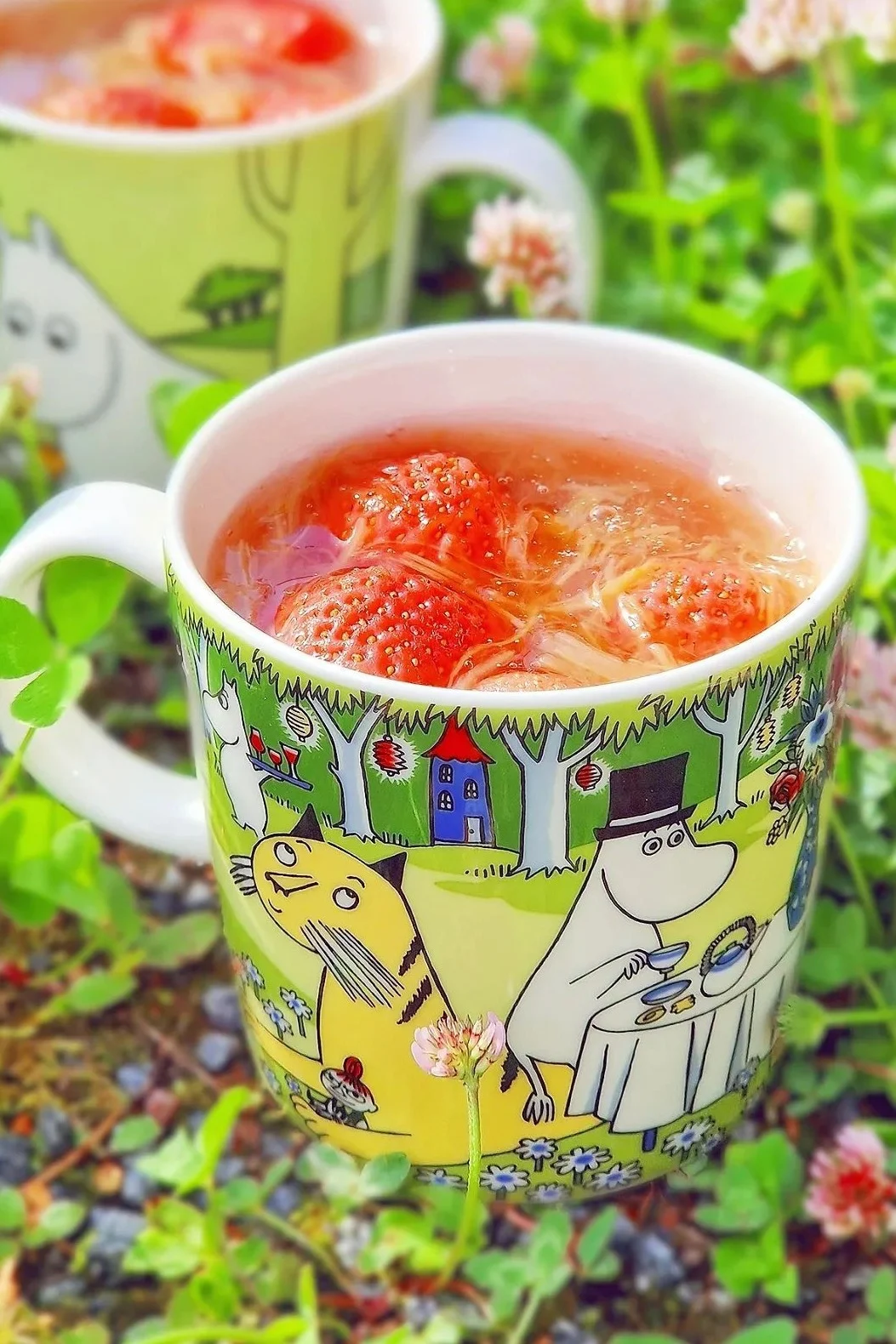 Die Mumin-Tasse vom Sommer 2023, "Garden Party", steht im Garten von @jasmiiniflower, gefüllt mit Himbeeren.