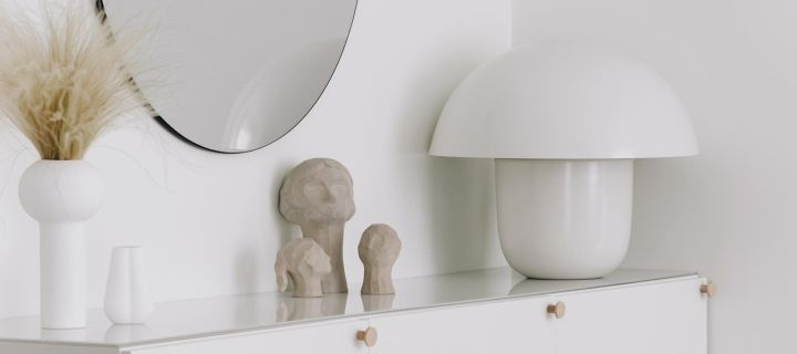 Flur gestalten – hier eine stilvolle Einrichtung auf einem Regal mit der Pillar Vase in Weiß, der Benedict und Amal Skulptur, der Ollie Skulptur von Cooee und der Carl-Johan Tischleuchte von Olsson & Jensen.