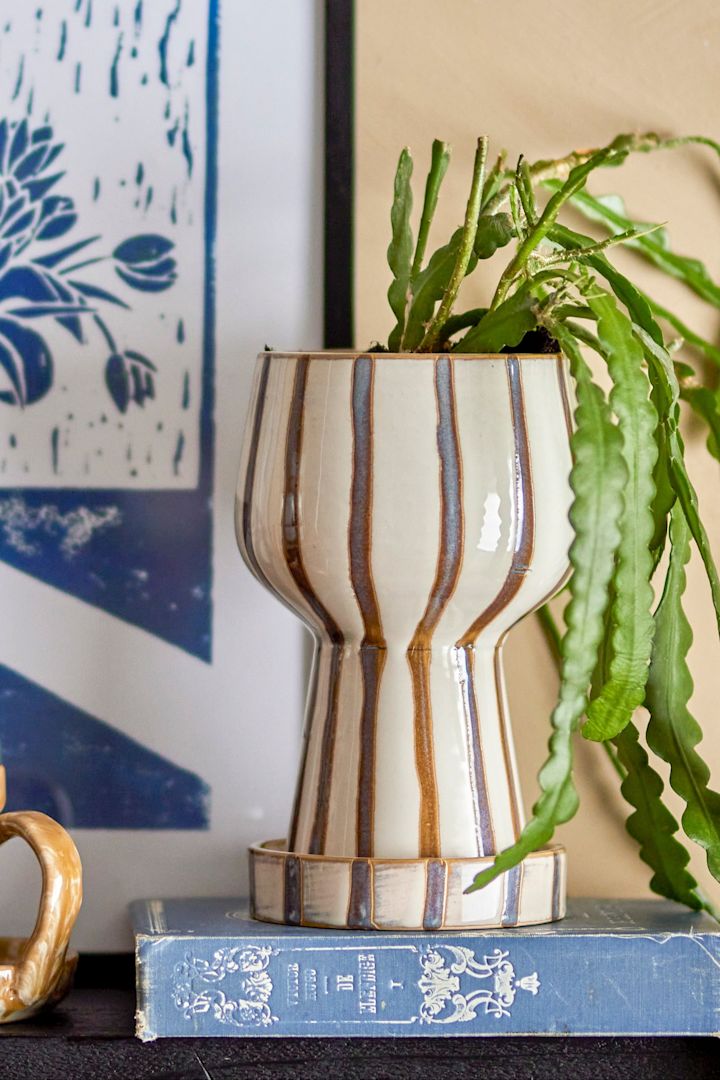 Die perfekte Boho Deko: Der gestreifte Blumentopf Agna mit einer Kelchform und einer Pflanze darin.