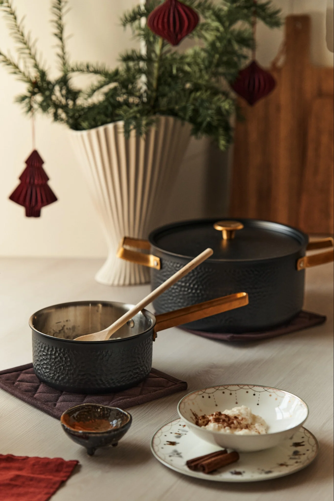 Ein Adventsfrühstück, gedeckt für den ersten Advent, mit der Kasserolle „Viggo” von Vargen & Thor. Auf dem Tisch steht die Kasserolle neben einem Teller mit Milchreis, Lebkuchen und einer Schüssel, im Hintergrund ist ein Weihnachtsbaum in einer Vase zu sehen.