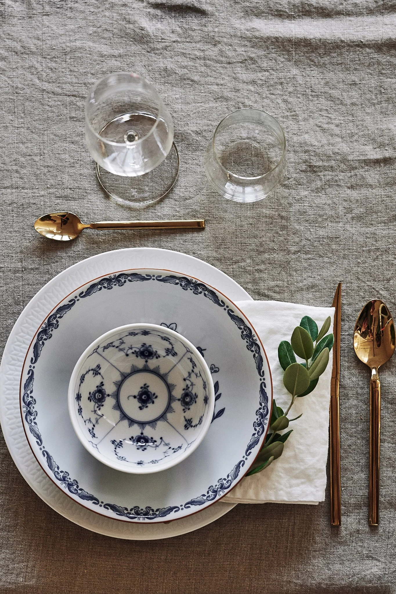 Ein Tipp für das Falten von Leinenservietten ist, sie doppelt zu falten und sie wie gezeigt zusammen mit einem grünen Zweig zwischen die Teller zu legen.