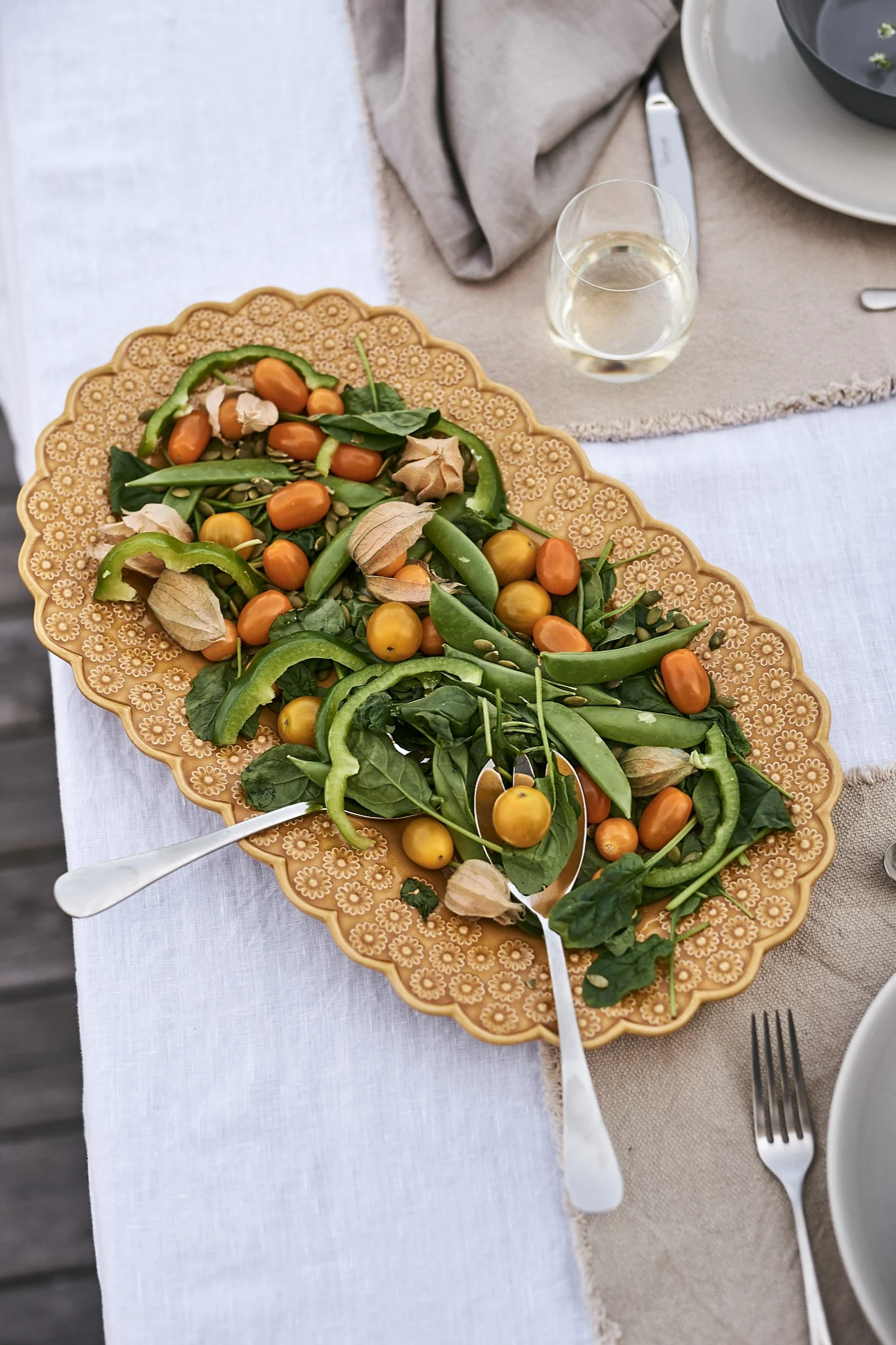 Ein herrlicher grüner Sommersalat wird beim Sommermittagessen auf einer gelben PotteryJo-Platte serviert.