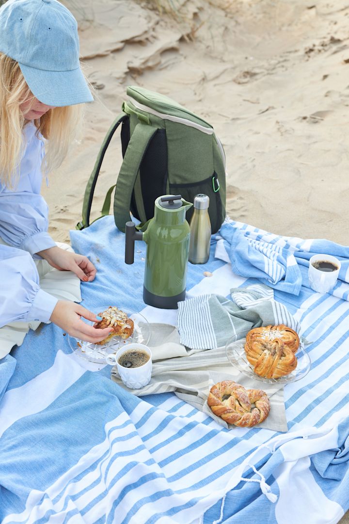 Ein sommerliches Picknick mit schwedischem Gebäck wird auf einer Decke am Strand serviert, dazu gibt es Kaffee aus der grünen Accent Kaffeekanne und den Picknick Tassen von Sagaform.