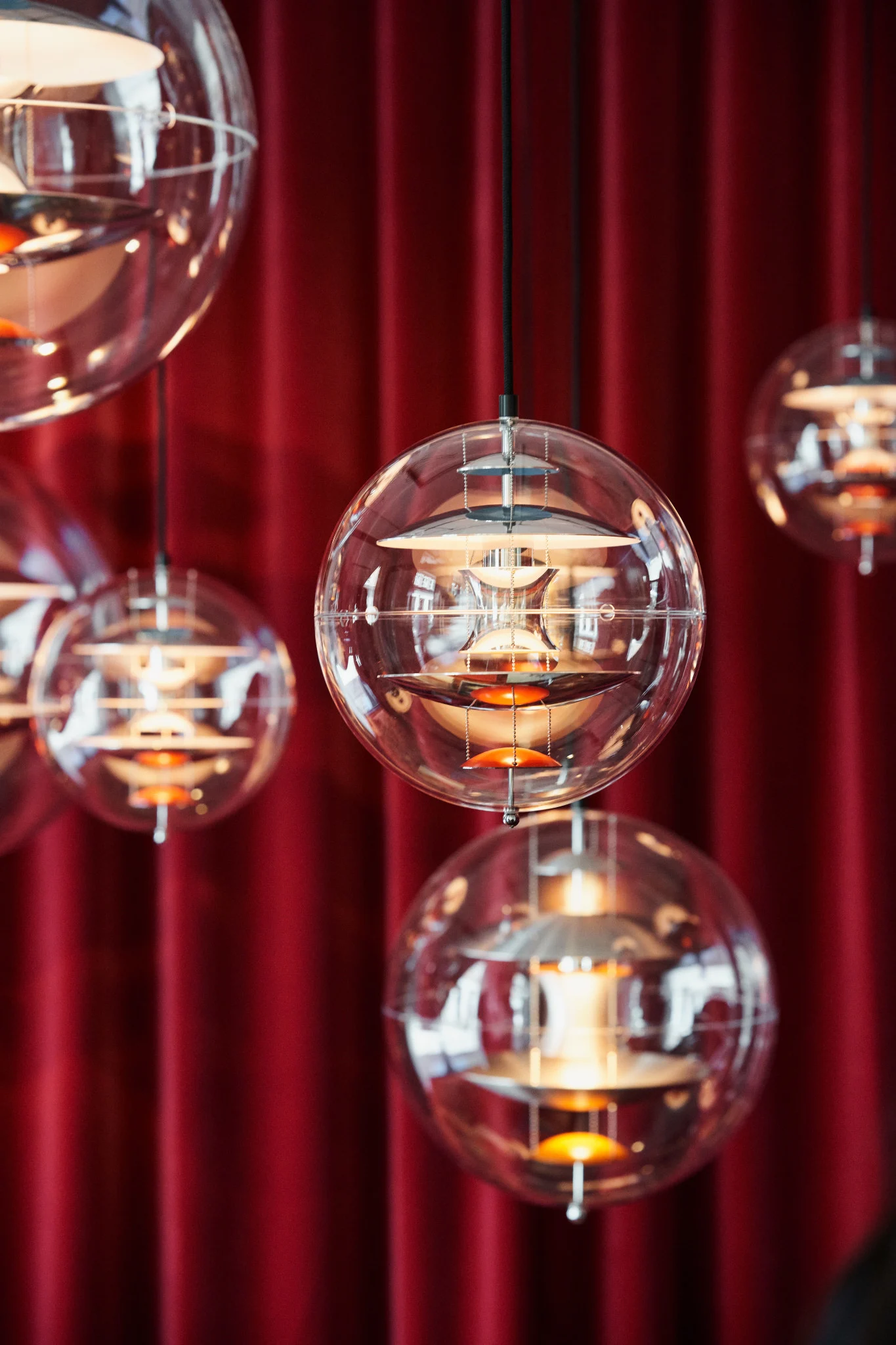 Mehrere Globe Glass Pendelleuchten von Verpan hängen vor einem roten Vorhang von der Decke.