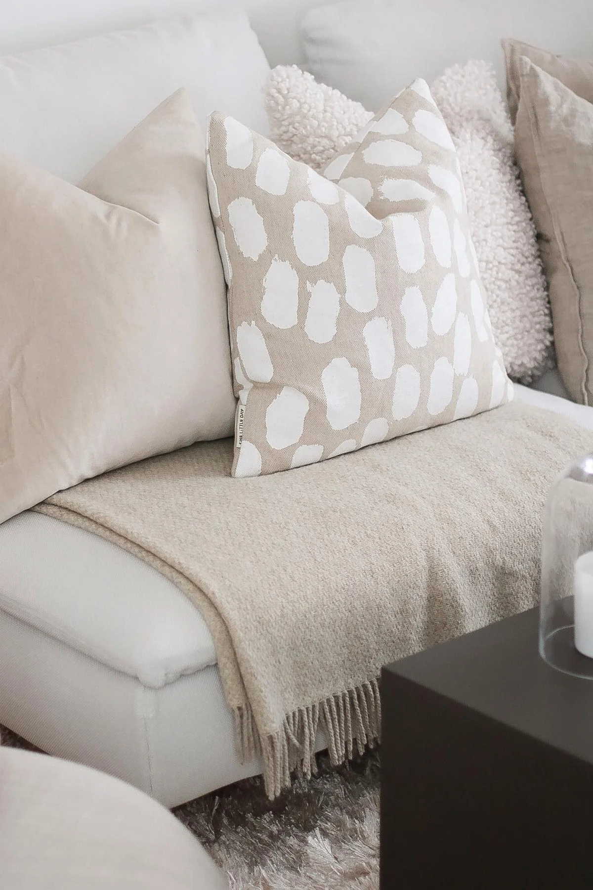 Auf der beigen Couch von @picsbyellen steht das beigefarbene Dots Kissen von Fine Little Day und die Sandstone Decke von Scandi Living.