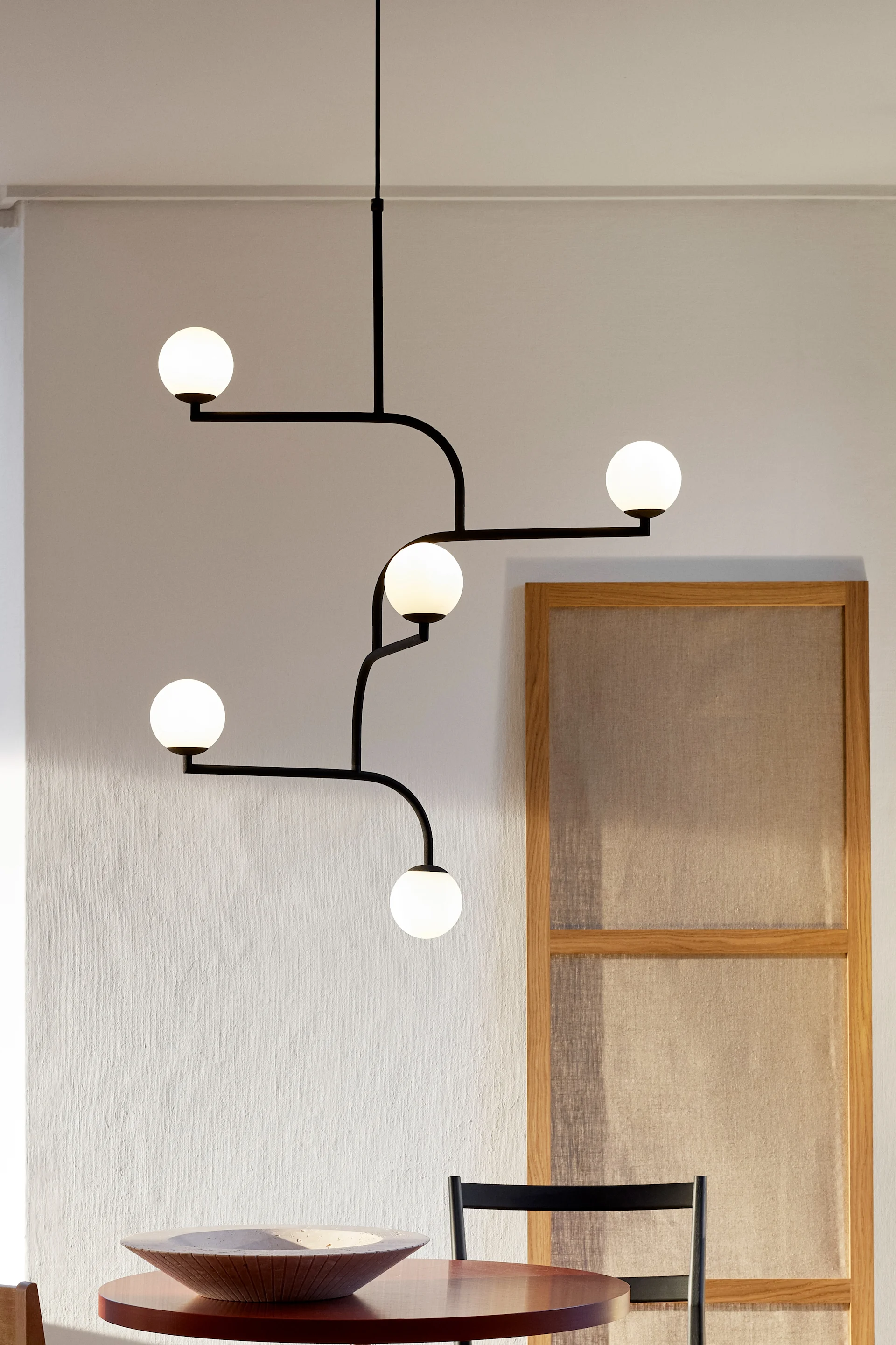 11 stylische Pendelleuchten für Ihr Wohlfühlzuhause - hier sehen Sie die Mobile 100 Pendelleuchte von Pholc, die über einem Esstisch hängt. 