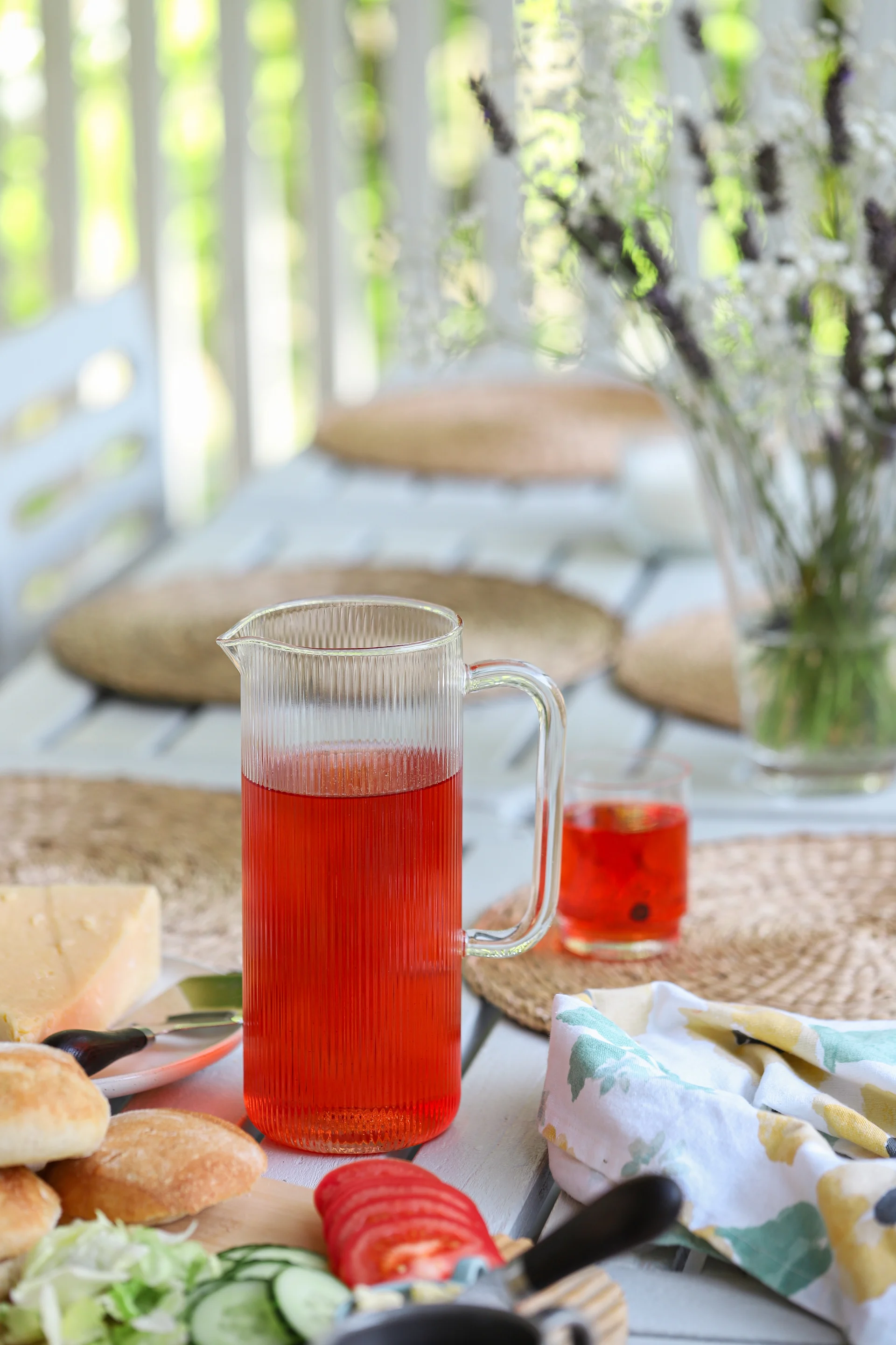Das Bild zeigt die Saga-Karaffe von Sagaform, gefüllt mit rotem Saft. Auf dem Tisch steht ein Frühstück mit Brötchen, geschnittenem Gemüse und Käse.
