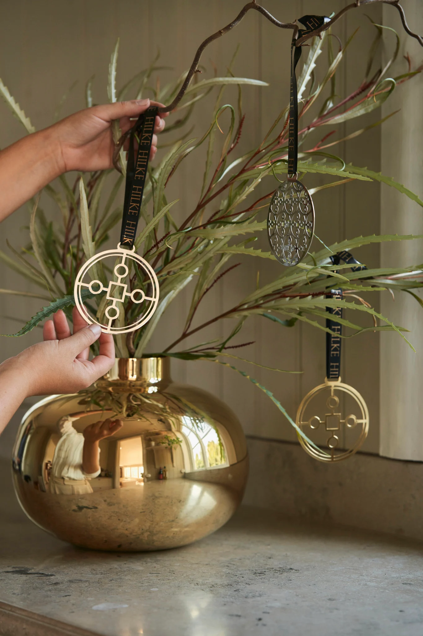 Um Ihren gedeckten Tisch ansprechend zu dekorieren, können Sie ein paar Zweige in die goldfarbene Amico Vase stellen und diese mit dem Anima Gemella Baumschmuck schmücken.