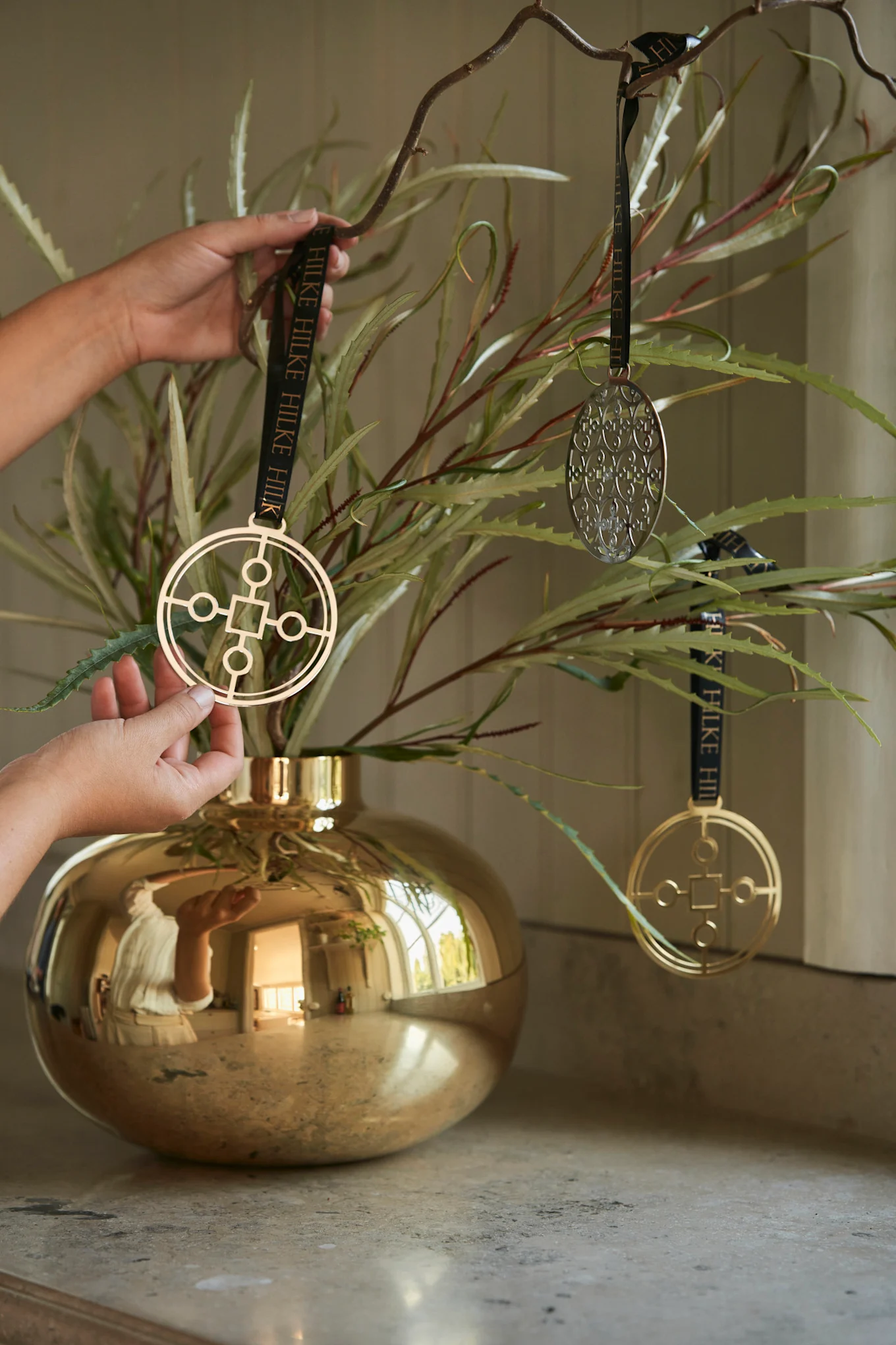 Um Ihren gedeckten Tisch ansprechend zu dekorieren, können Sie ein paar Zweige in die goldfarbene Amico Vase stellen und diese mit dem Anima Gemella Baumschmuck schmücken.