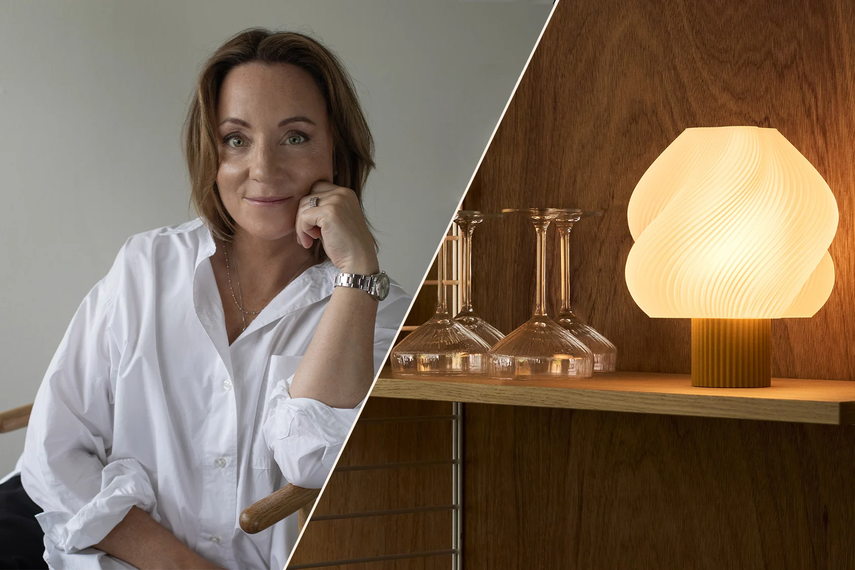 Lächelnde Frau in weißem Hemd, Kinn auf der Hand, eine Uhr tragend, in einem warmen, modernen Interieur mit Regalen und einer Lampe.