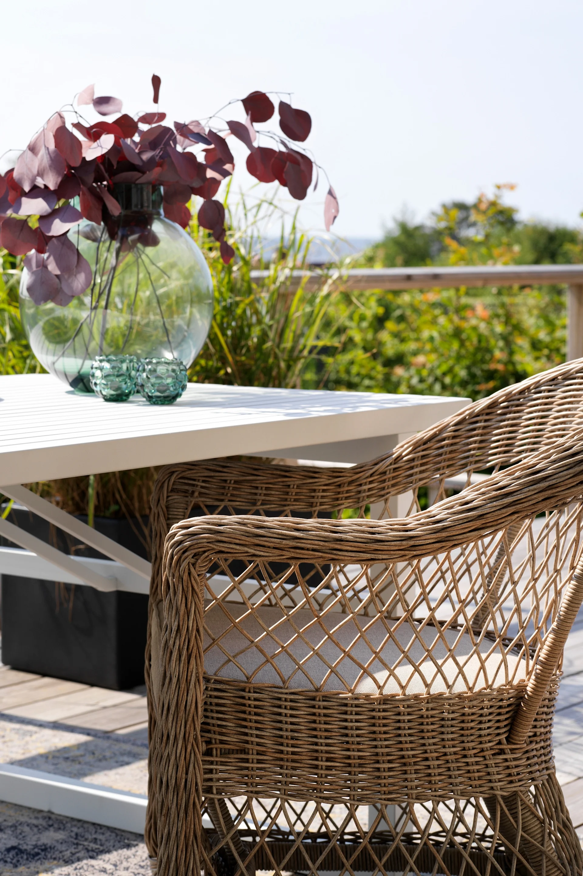 Der Kamomill Armlehnenstuhl von Brafab steht auf einer Terrasse an einem Tisch.