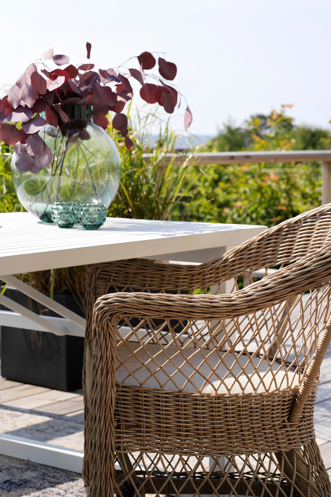 Der Kamomill Armlehnenstuhl von Brafab steht auf einer Terrasse an einem Tisch.